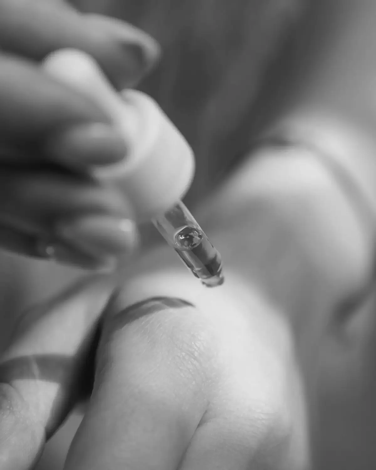 A glass dropper held close to the skin