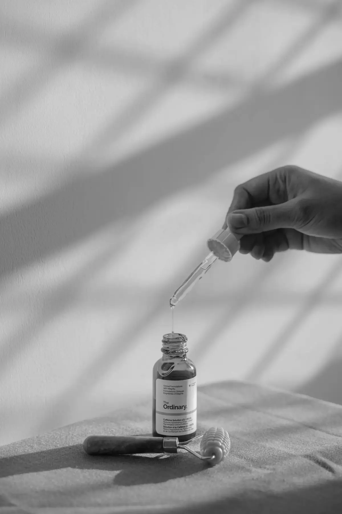 Serum dropped into a bottle in striped sunlight