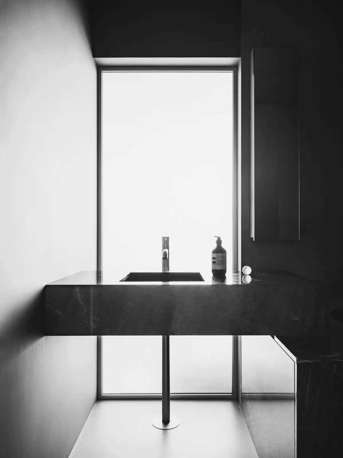 A calm treatment room with tall window light and a stone basin