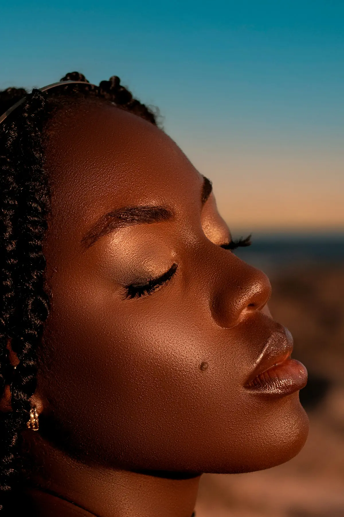 A woman in golden evening light, eyes closed, skin glowing