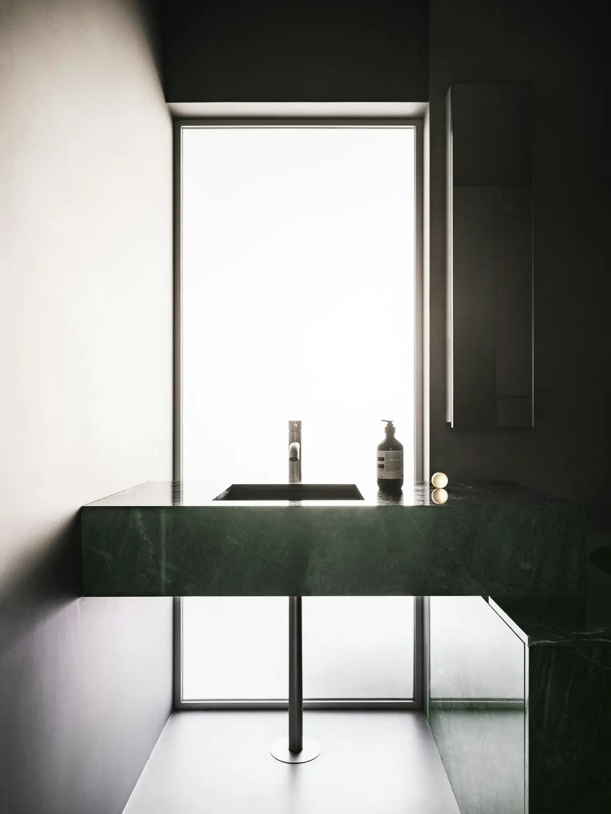 A calm treatment room with tall window light and a stone basin