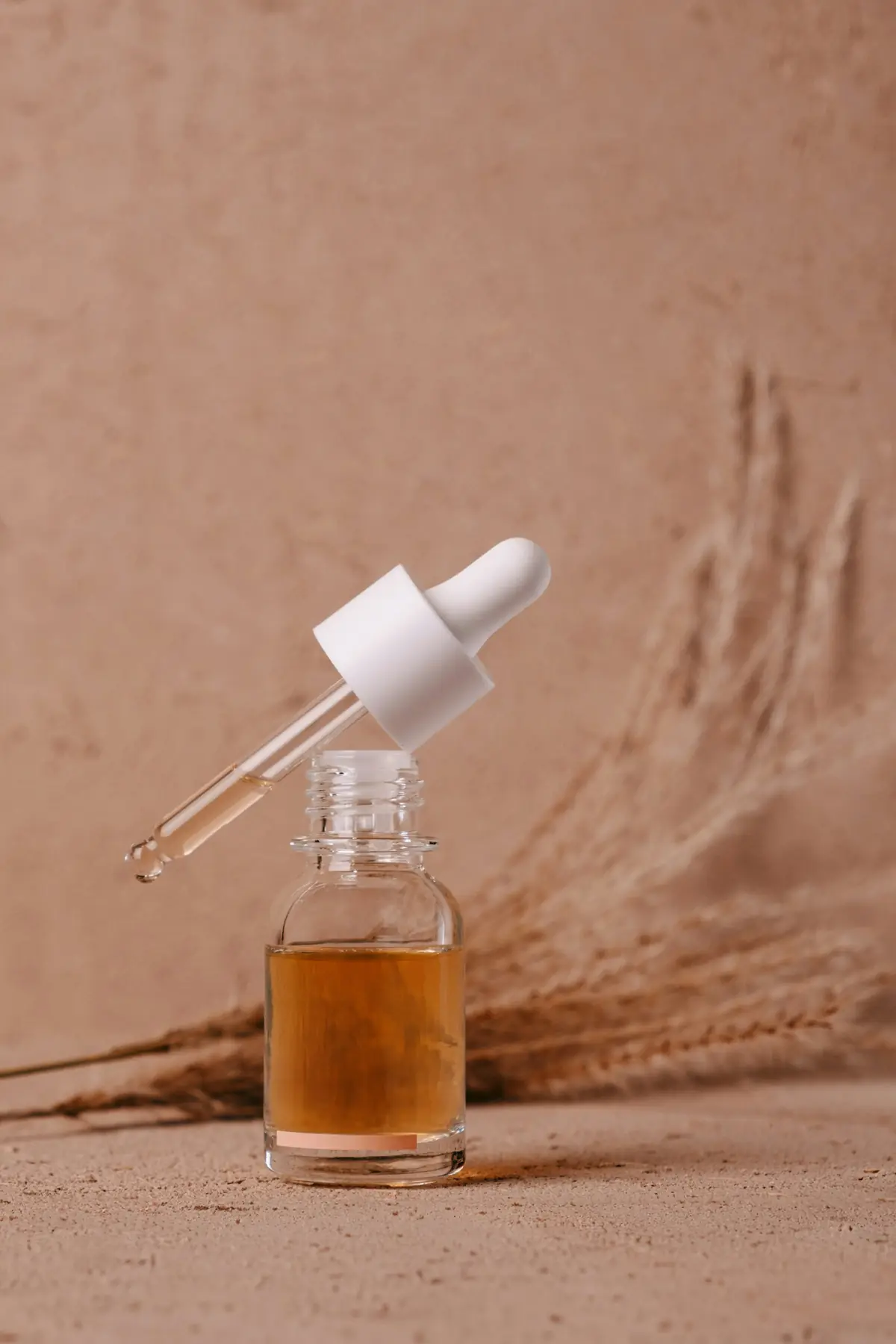 A dropper bottle of amber serum in warm light